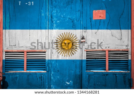Close-up of old warehouse gate with national flag of Argentina. Concept of Argentina export-import, storage of goods and national delivery of goods. Flag in grunge style