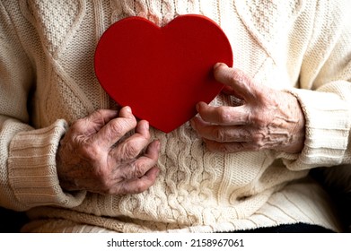 Closeup Of Old Woman Hands Hold Red Heart -  Concept Of Heart Health And Quality Of Life For Elderly