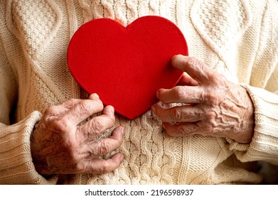 Closeup Of Old Woman Hands Hold Red Heart -  Concept Of Heart Health And Quality Of Life For Elderly