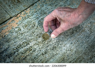 Close-up Of Old Womans Hand Picking Up A Coin From The Floor