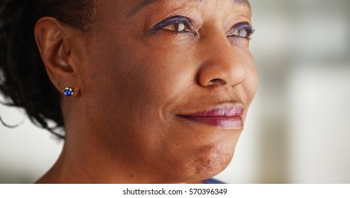 A close-up of an older black woman being very happy