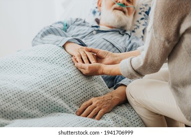 Nahaufnahme eines älteren sterbenden Mannes, der die Hände seiner Frau hält