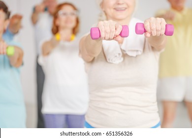 Close-up of older woman exercising shoulders with dumbbells