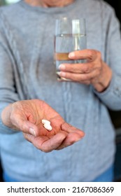 Close-up Of An Older Woman Holding Pills And Glass Of Water