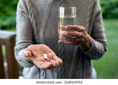 Close-up Of An Older Woman Holding Pills And Glass Of Water