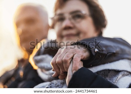 Close-up of an older woman holds the hand of an older man, showing a  love, support, and companionship in their relationship.