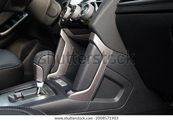 Close-up on automatic transmission lever in modern\
car. Car interior details. Transmission shift. Decorative panels in\
the finish in the car