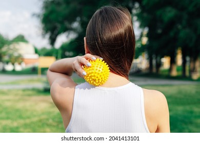 Close-up On Back Of Young Woman Doing Neck And Shoulder Massage With Spiky Rubber Ball, Relaxing Tense Neck Muscles. 