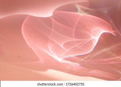 Close-up on beautiful shadow of glass or crystal object. Caustic effect as light passes through. Sun hard light shadow reflection. Shadows from glasses on light pink or purple background.
