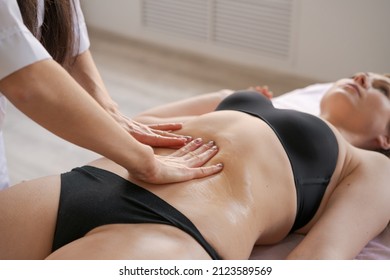 Close-up on belly woman having anti-cellulite massage session with madero therapy, professional therapist holding wooden tools in studio or salon with copy space
