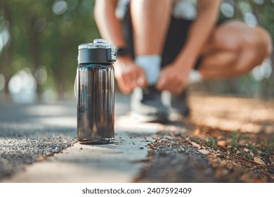 Closeup on black bottle of water, Blurred man tie their shoes before run on track race in the public park, Healthy - Powered by Shutterstock