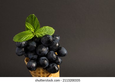 Close-up on black grape in the ice cream cone on the dark background. Copy space.
