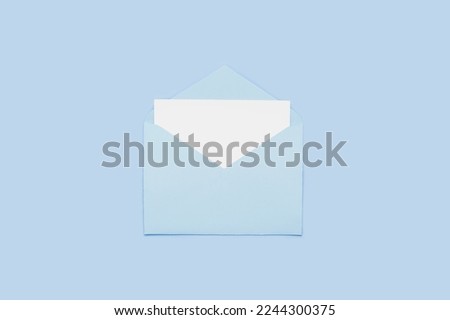 Closeup on blank empty white paper card in blue opened envelope isolated on blue pastel color background. Love letter minimal concept. Conceptual layout template with text place on postcard. Mock-up 