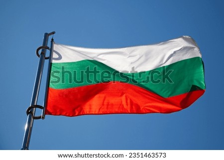 Close-up on a Bulgarian flag waving atop of its pole.