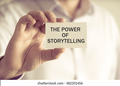 Closeup on businessman holding a card with text THE POWER OF STORYTELLING, business concept image with soft focus background and vintage tone