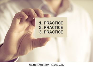 Closeup on businessman holding a card with text PRACTICE, PRACTICE, PRACTICE, business concept image with soft focus background and vintage tone
