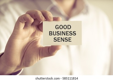 Closeup On Businessman Holding A Card With Text GOOD BUSINESS SENSE, Business Concept Image With Soft Focus Background And Vintage Tone