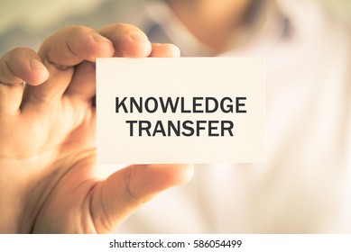 Closeup On Businessman Holding A Card With Text KNOWLEDGE TRANSFER, Business Concept Image With Soft Focus Background And Vintage Tone