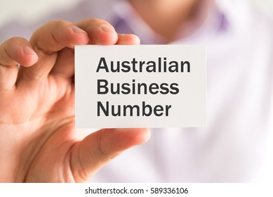 Closeup on businessman holding a card with ABN AUSTRALIAN BUSINESS NUMBER message, business concept image with soft focus background and vintage tone