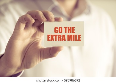 Closeup On Businessman Holding A Card With Text GO THE EXTRA MILE, Business Concept Image With Soft Focus Background And Vintage Tone