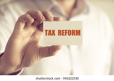 Closeup on businessman holding a card with text TAX REFORM, business concept image with soft focus background and vintage tone