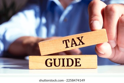 Closeup on businessman holding a wooden block with "TAX GUIDE", Business concept - Shutterstock ID 2258474149