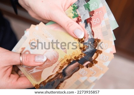 closeup on Canadian dollars in various denominations. A woman is counting Canadian money. Canadian economics and finance
