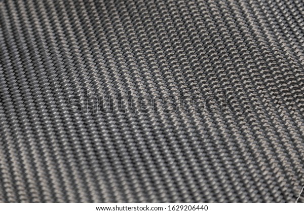 A close-up on a carbon fiber\
background of interwoven black and gray color from heavy-duty yarns\
for the production of light and durable elements in\
industry.