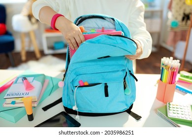 Closeup On Child With Workbooks And Blue Backpack Packing For School At Home In Sunny Day.