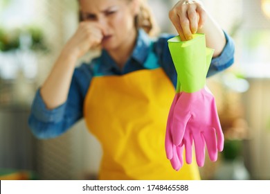 Closeup On Disgusted Woman In Orange Apron And Pink Rubber Gloves In The Living Room In Sunny Day Holding Smelly Gloves.