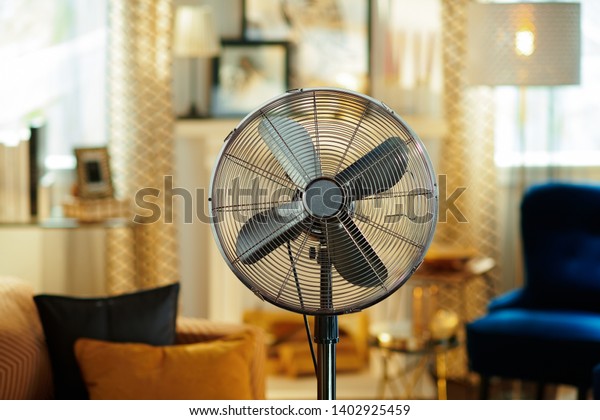 Closeup on electric floor standing fan in\
the modern living room in sunny hot summer\
day.