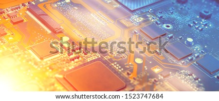 Closeup on electronic motherboard card in hardware repair shop. Blurred panoramic image with details of the circuitry and close-up on electronics. Filtered picture toned in orange and blue, copy-space