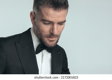 closeup on an elegant businessman looking down, being dramatic and wearing a black tuxedo 