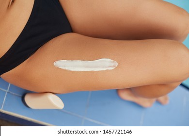 Closeup on female hand applying sunscreen creme on beautiful legs. Skincare. Sun protection sun cream, on her smooth tanned legs.Sexy Woman with perfect body in bikini lying on beach
