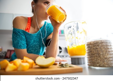 Close-up on fitness young woman drinking pumpkin smoothie in kitchen
