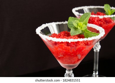 Nahaufnahme von gefrorenem Saft mit Erdbeeren in der Martini-Brille auf schwarzem Hintergrund
