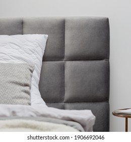 Close-up on gray and quilted and upholstered headboard of comfortable bed