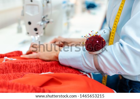 Close-up on the hand and works of an alterations tailor at her sewing machine
