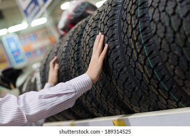 Closeup On Hands Of Man Or Woman Touching & Choosing For Buying A Tire In A Supermarket Shop Or DIY Department Store With Shopping Shelf On The Background