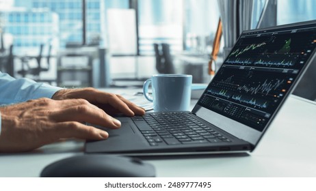 Close-Up On Hands Of Professional Financial Analyst Using Laptop Computer With Stock Options Graphs And Charts On Screen. Man Analyzing Stock Market Data And Enjoying Coffee In Hedge Fund Office. - Powered by Shutterstock