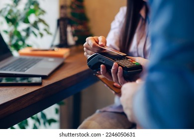 Close-up on hands. Woman paying for order with credit card NFC technology using bank terminal