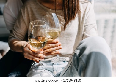 Close-up On Hands Of Young Couple Of Man And Woman In Casual Clothes, Sitting On Windowsill In Day Light Hugging And Drinking Wine.