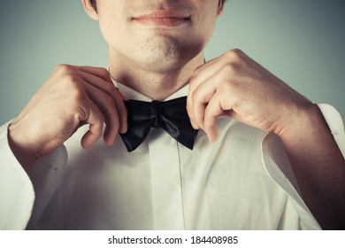 Closeup on a happy young man tying a bow tie