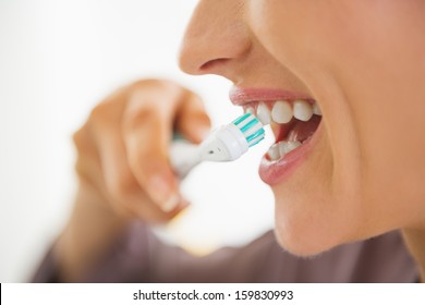 Closeup on happy young woman brushing teeth