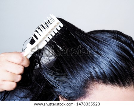 Close-up on head of Asian people have long black hair, combing hair with hairbrush. Black and thick hair health.