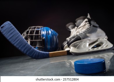 Close-up on hockey puck and hockey equipment in background.
