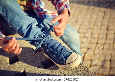 Closeup on kid hands tying laces ready for sport, school fun. Outside sunny background - Powered by Shutterstock