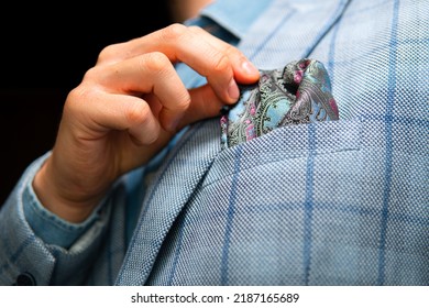Close-up on a man adjusting a pocket square in a breast pocket