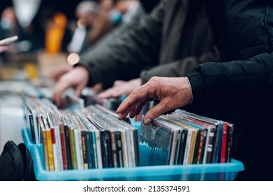 Close-up on man hands browsing vinyl album in a record store. People visit vinyl second hand market. Vinyl album on sale.