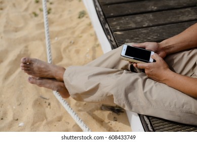 Closeup on man sitting using mobile phone. Portable computer mockup display outdoors background
